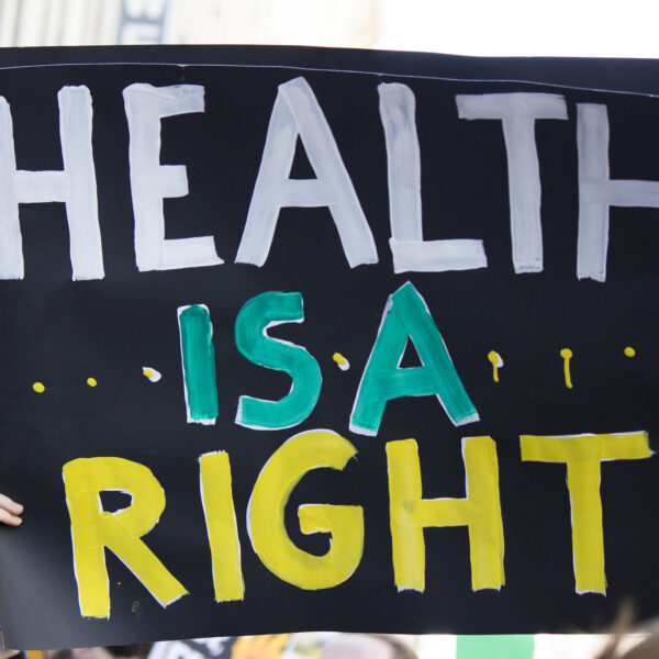 Schild auf einer Demo, das hochgehoben wird und auf dem der Text "Health is a right" in Blockbuchstaben geschrieben ist