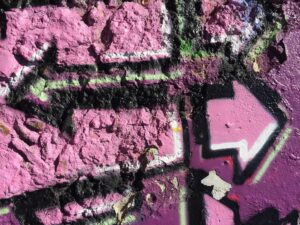 pink-lila Graffito mit Pfeilen, die in unterschiedliche Richtungen weisen