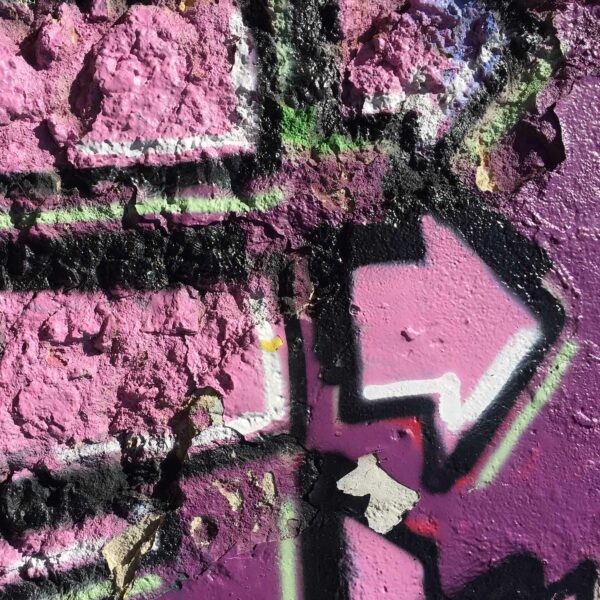 pink-lila Graffito mit Pfeilen, die in unterschiedliche Richtungen weisen