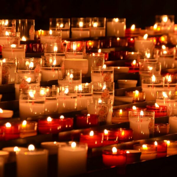 Eine Menge an brennenden Kerzen mit roten und transparenten Kerzengläsern