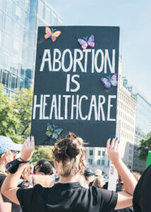 Demonstration, eine Person hält ein Schild mit dem Text "Abortion is healthcare"