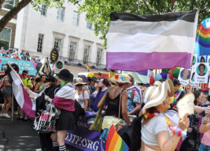 Asexualität-Pride-Fahne (von oben nach unten: gestreift in schwarz, grau, weiß, violett), die hoch über den Köpfen von Pride-Parade-Besucher*innen weht