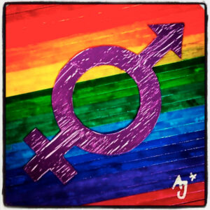 Kunst von Alex Jürgen*: ein Geschlechtersymbol, das die Symbole von Frau und Mann vereint und in lila gehalten ist, im Hintergrund sind Regenbogenfarben. Das Bild besteht aus Papierstreifen.