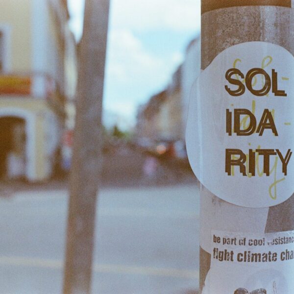 Sticker mit dem Text "Solidarity", angebracht im öffentlichen Raum. Darunter ein zweiter Sticker mit dem Text "be part of cool resistance. fight climate change"
