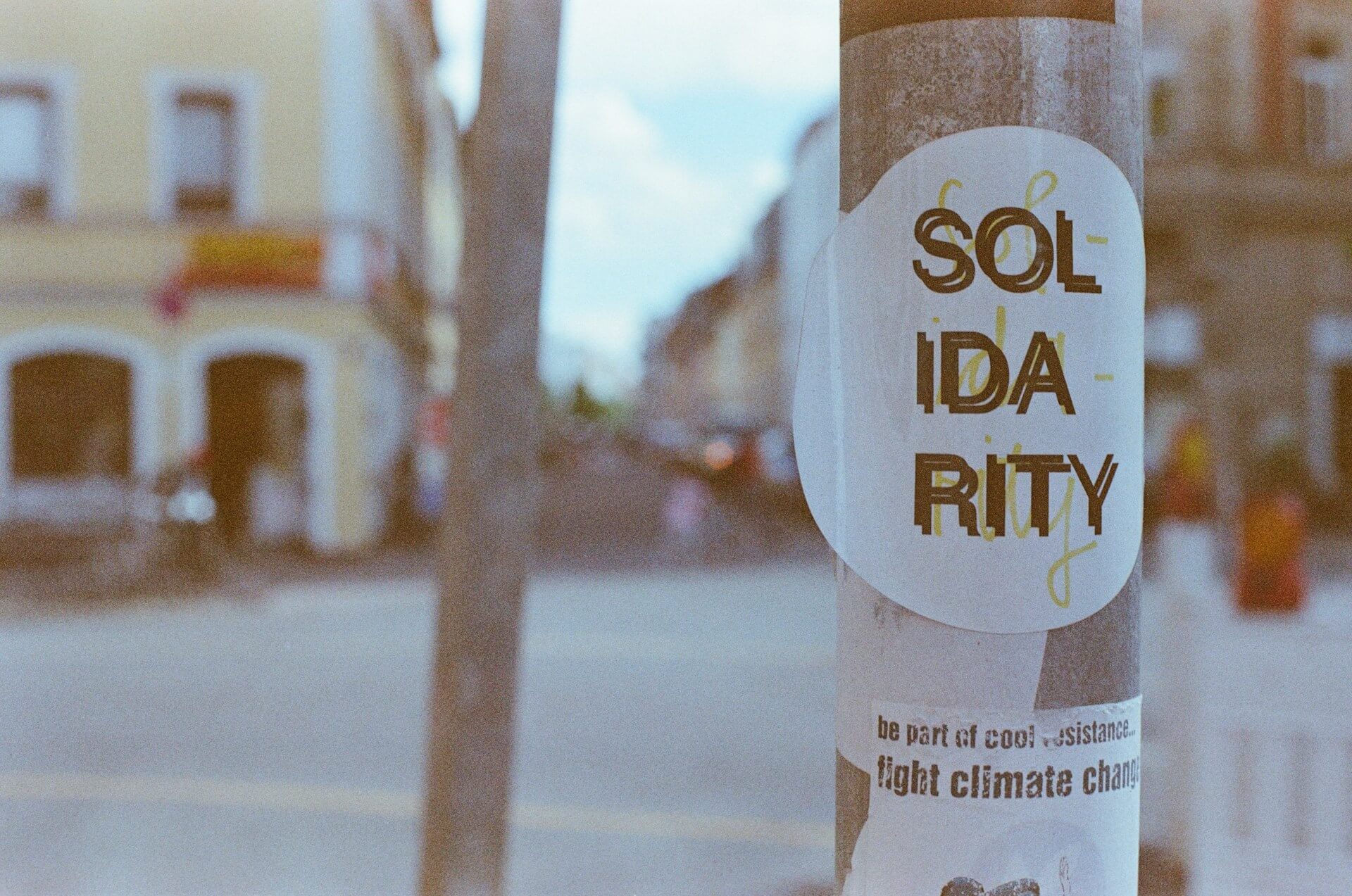 Sticker mit dem Text "Solidarity", angebracht im öffentlichen Raum. Darunter ein zweiter Sticker mit dem Text "be part of cool resistance. fight climate change"
